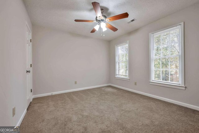 empty room with ceiling fan, a textured ceiling, and carpet flooring