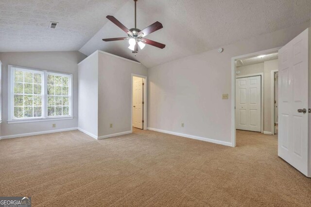 carpeted spare room with ceiling fan, a textured ceiling, and lofted ceiling