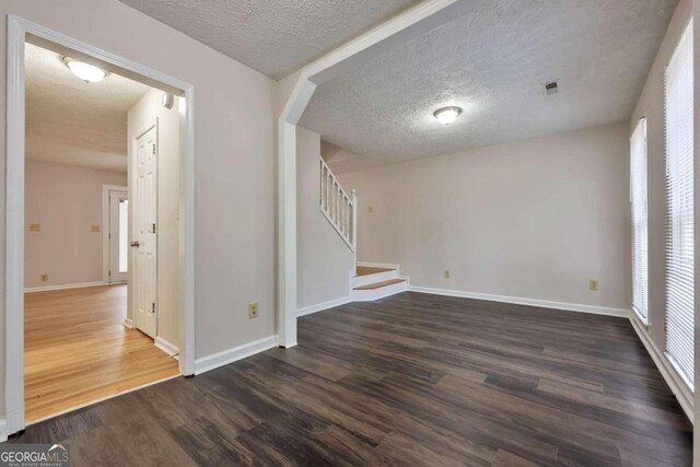 unfurnished room featuring dark wood-type flooring and a textured ceiling