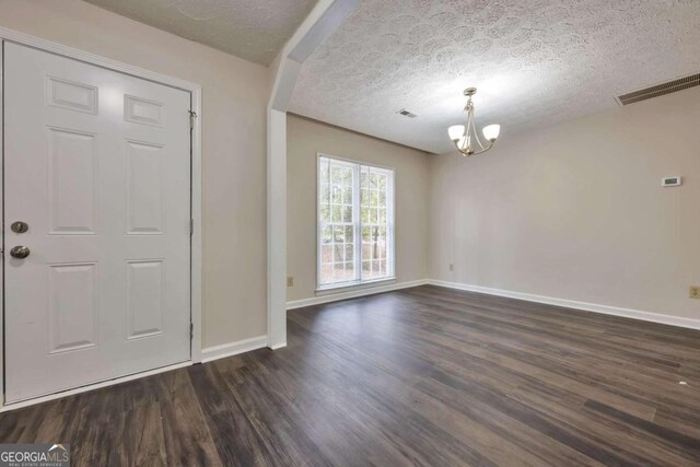 entrance foyer with a chandelier, a textured ceiling, and dark hardwood / wood-style floors