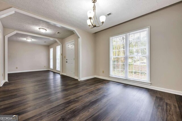 entrance foyer featuring dark hardwood / wood-style flooring, a textured ceiling, and a notable chandelier