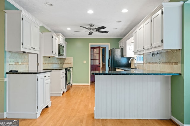 kitchen featuring light hardwood / wood-style floors, kitchen peninsula, appliances with stainless steel finishes, ornamental molding, and white cabinets