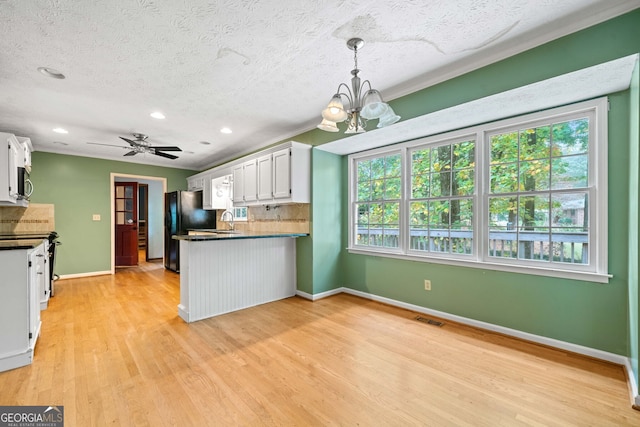 kitchen with black refrigerator, light hardwood / wood-style flooring, a wealth of natural light, and white cabinets