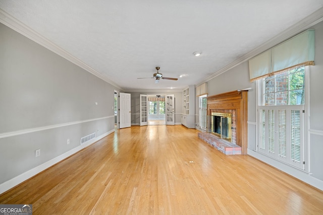 unfurnished living room with a brick fireplace, light hardwood / wood-style floors, plenty of natural light, and crown molding