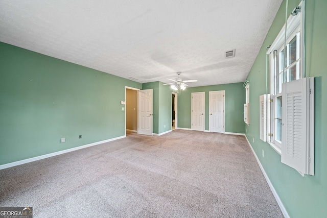 carpeted spare room with ceiling fan and a textured ceiling