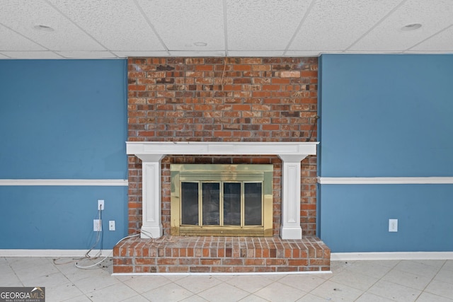 unfurnished living room with a brick fireplace and a drop ceiling