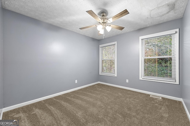 carpeted empty room with ceiling fan and a textured ceiling