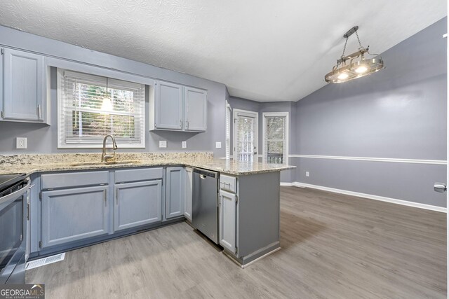 kitchen with sink, stainless steel appliances, kitchen peninsula, pendant lighting, and light wood-type flooring