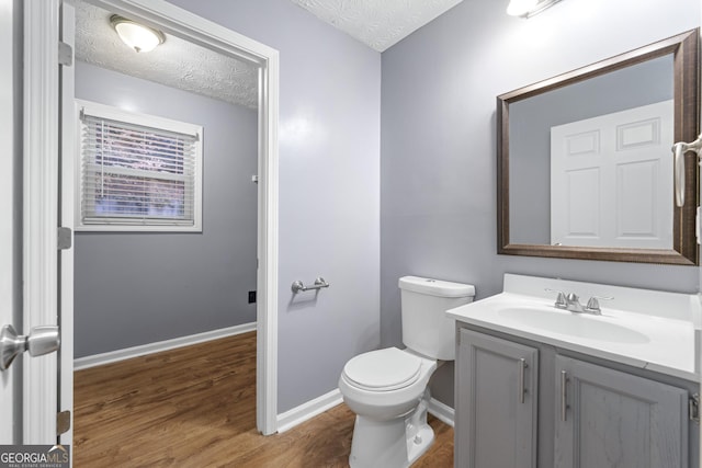 bathroom featuring vanity, wood-type flooring, a textured ceiling, and toilet