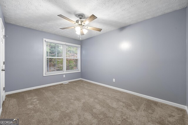 carpeted empty room featuring ceiling fan and a textured ceiling