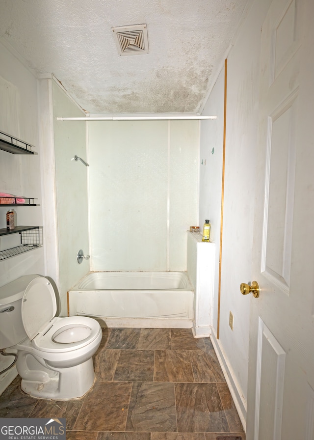 bathroom featuring shower / washtub combination, a textured ceiling, and toilet