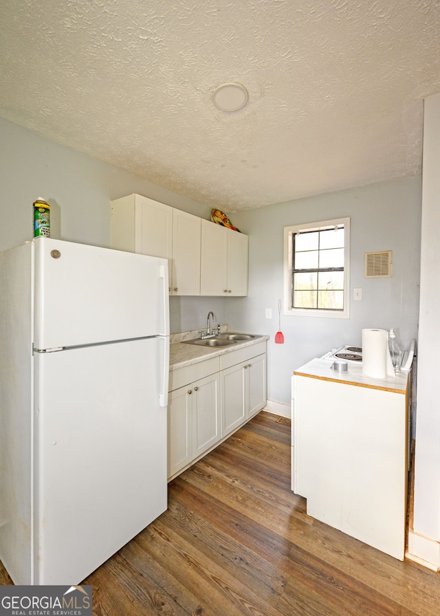 kitchen featuring dark hardwood / wood-style flooring, white cabinetry, sink, and white refrigerator