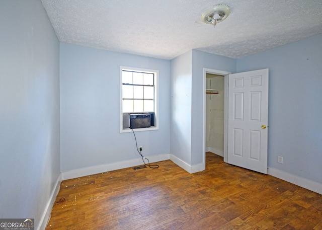 spare room featuring a textured ceiling, cooling unit, and dark hardwood / wood-style floors