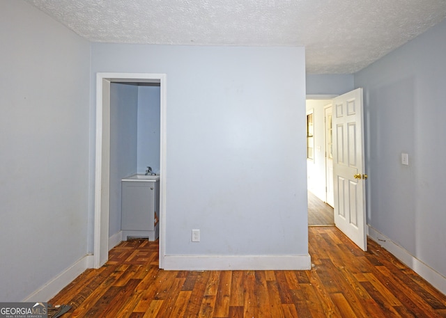 unfurnished room with dark hardwood / wood-style floors, sink, and a textured ceiling