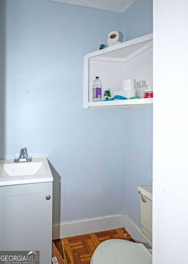 bathroom with parquet flooring, vanity, a textured ceiling, and toilet