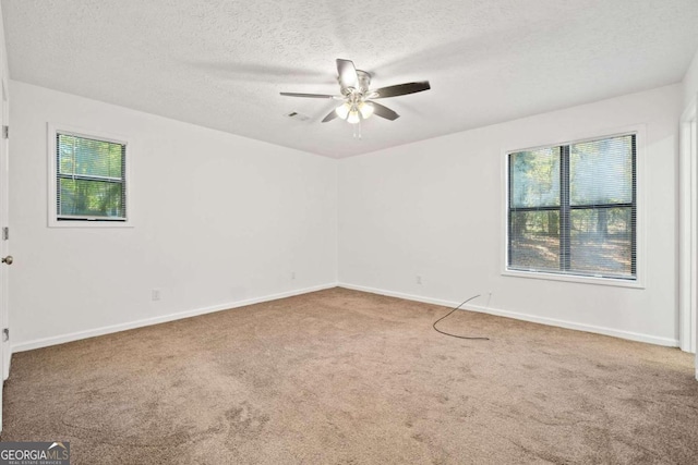 carpeted spare room with a textured ceiling, a healthy amount of sunlight, and ceiling fan