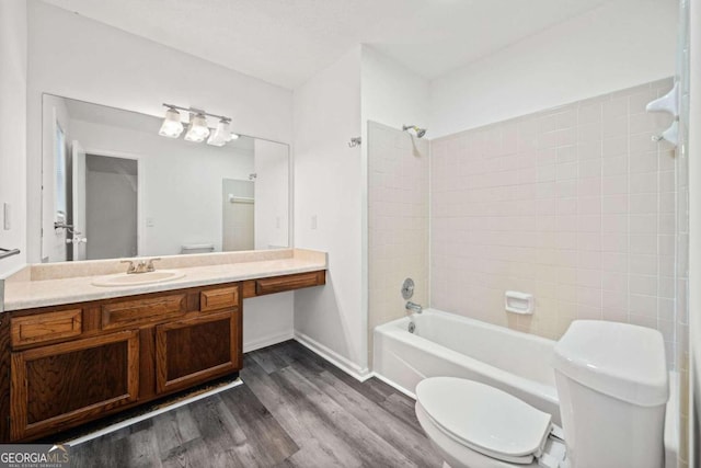 full bathroom with hardwood / wood-style floors, vanity, tiled shower / bath combo, and toilet