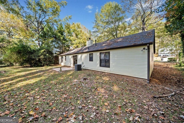 back of house with central AC unit and a yard