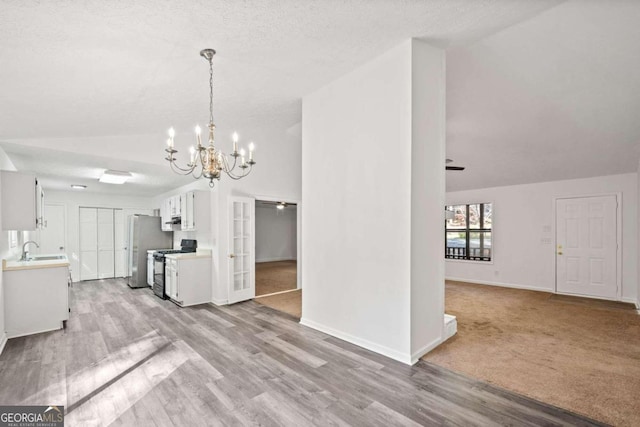 kitchen with black gas stove, white cabinetry, sink, and lofted ceiling