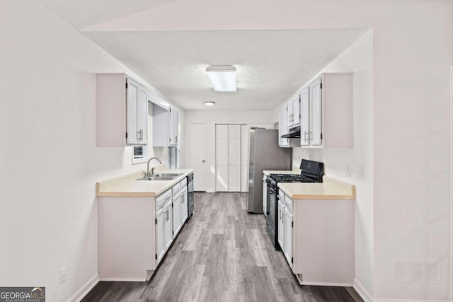 kitchen with white cabinets, black gas stove, sink, and light hardwood / wood-style flooring