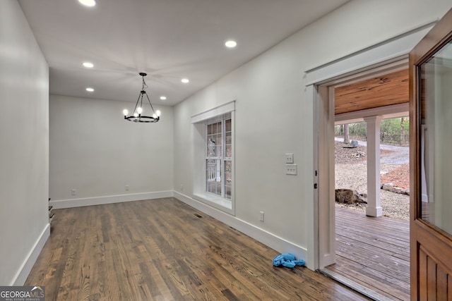 unfurnished dining area with a notable chandelier and dark hardwood / wood-style floors