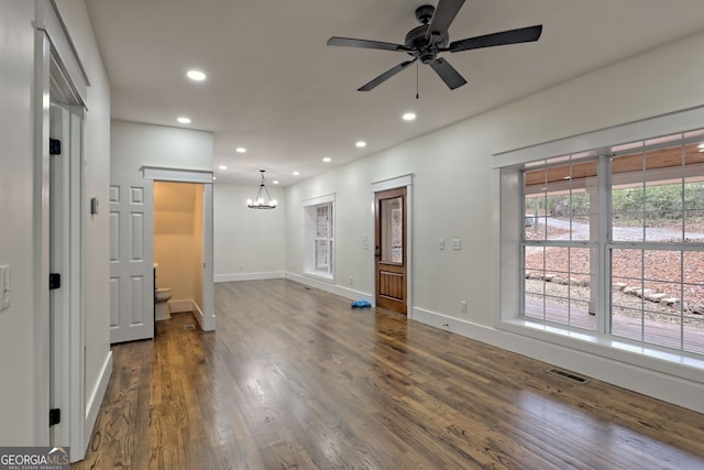 interior space with ceiling fan with notable chandelier and dark hardwood / wood-style floors