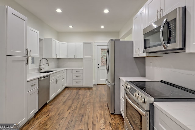 kitchen with light stone counters, white cabinetry, appliances with stainless steel finishes, sink, and dark wood-type flooring