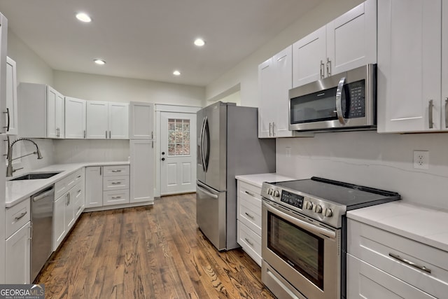 kitchen featuring stainless steel appliances, sink, light stone counters, dark hardwood / wood-style floors, and white cabinets