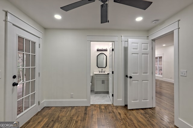 unfurnished bedroom with multiple windows, dark hardwood / wood-style floors, ceiling fan, and connected bathroom