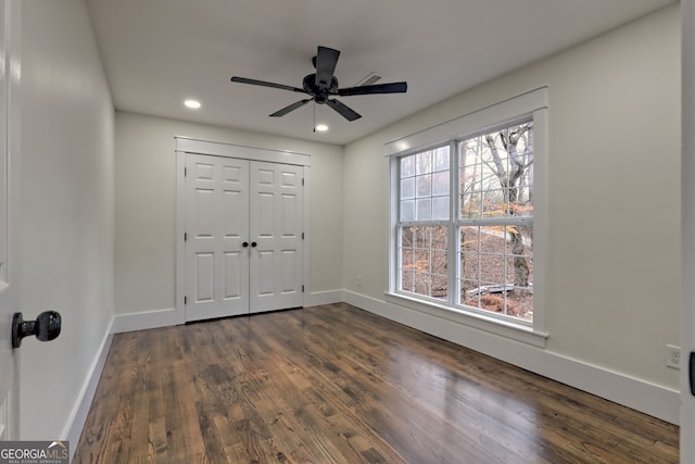 unfurnished bedroom with dark wood-type flooring, ceiling fan, and a closet