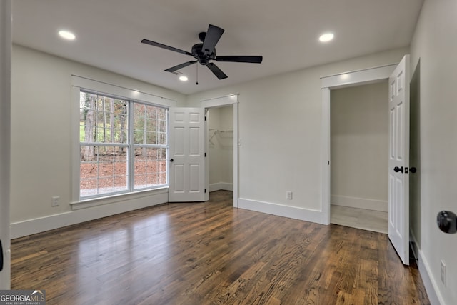 unfurnished bedroom featuring dark hardwood / wood-style flooring, ceiling fan, a walk in closet, and a closet