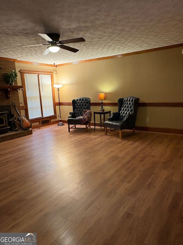 sitting room with ornamental molding, wood-type flooring, ceiling fan, and a textured ceiling