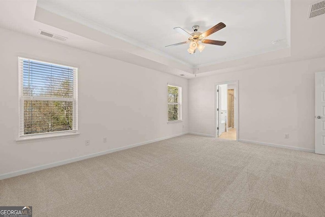 unfurnished room with light carpet, ceiling fan, and a tray ceiling