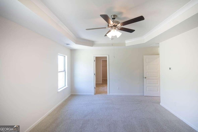 carpeted empty room featuring ceiling fan, ornamental molding, and a raised ceiling