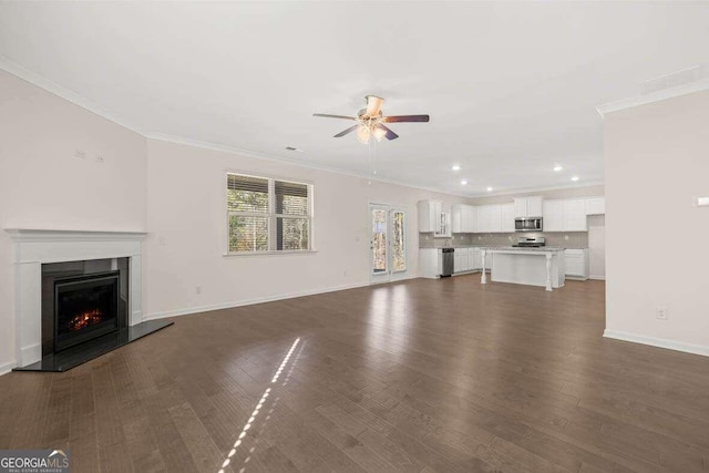 unfurnished living room with crown molding, ceiling fan, and dark wood-type flooring