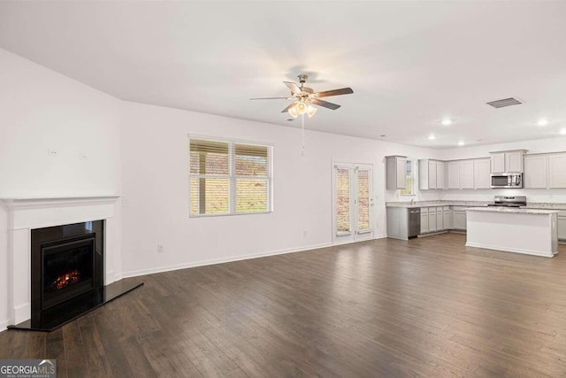 unfurnished living room with dark hardwood / wood-style flooring, ceiling fan, and a healthy amount of sunlight