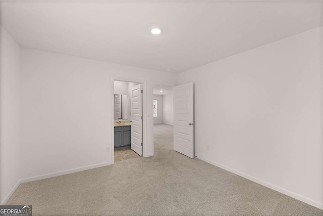 unfurnished bedroom featuring light colored carpet and ensuite bathroom