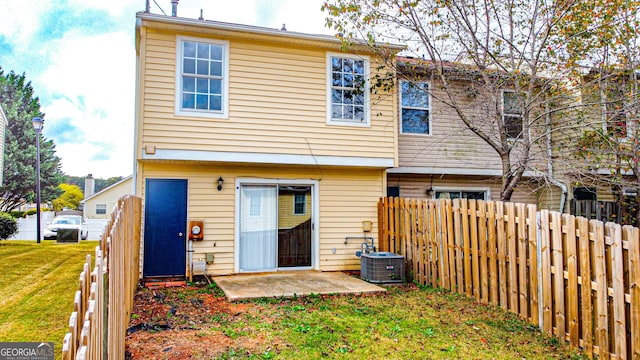 rear view of house featuring central air condition unit, a lawn, and a patio