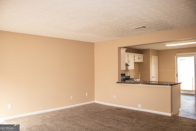 kitchen with kitchen peninsula, white cabinetry, carpet flooring, and black stove