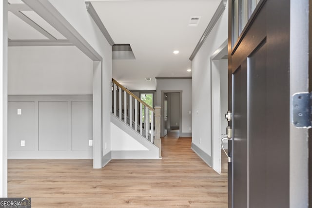 foyer with light hardwood / wood-style flooring and crown molding