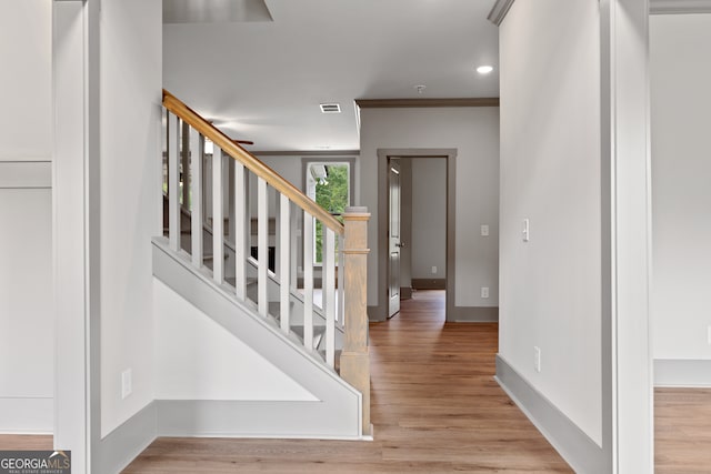 foyer entrance with light hardwood / wood-style flooring and ornamental molding