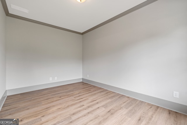 spare room with ornamental molding and light hardwood / wood-style flooring