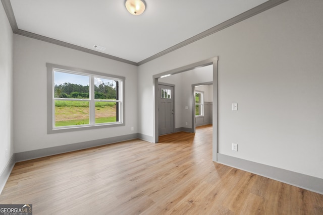 spare room featuring light wood-type flooring and crown molding