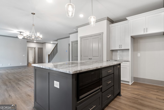 kitchen with white cabinetry, pendant lighting, light wood-type flooring, and ornamental molding