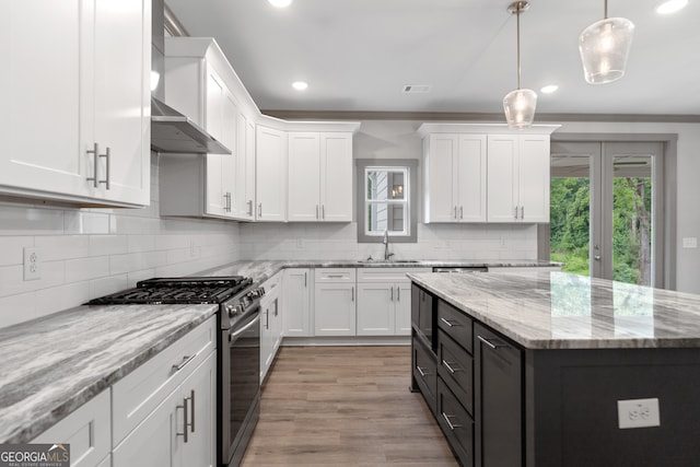 kitchen with pendant lighting, a center island, stainless steel gas range oven, light hardwood / wood-style floors, and white cabinetry