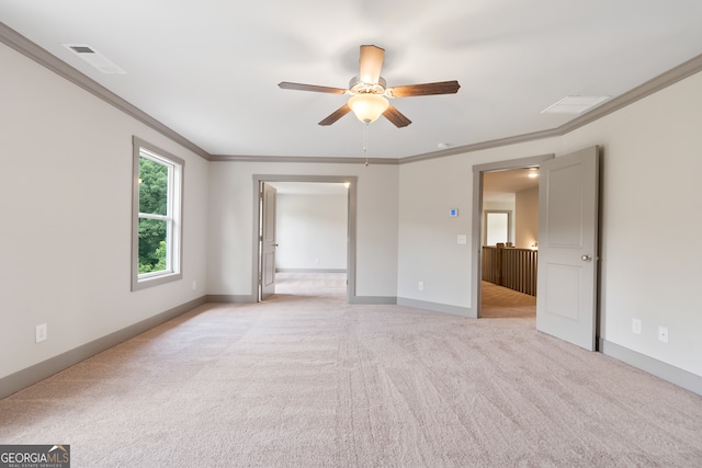 spare room featuring ceiling fan, ornamental molding, and light carpet