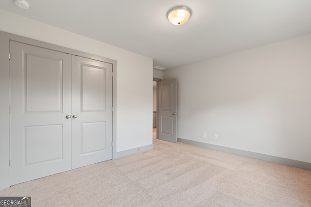 unfurnished bedroom featuring light colored carpet and a closet