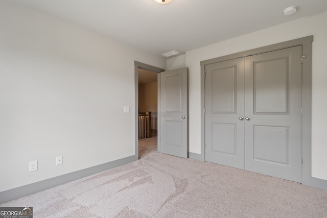 unfurnished bedroom with light carpet and a closet