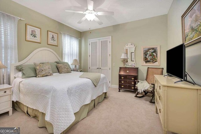 bedroom featuring ceiling fan, light carpet, and a closet