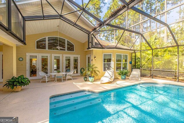 view of pool featuring a patio, ceiling fan, glass enclosure, and french doors